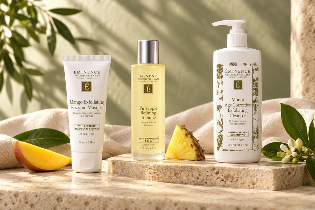 Éminence exfoliating skincare arranged with fruit and botanicals on cream stone.