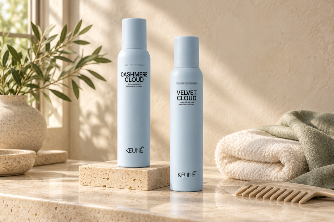 Keune Cashmere Cloud and Velvet Cloud styling foams beside a comb, cream towel and sage linen on a stone vanity.