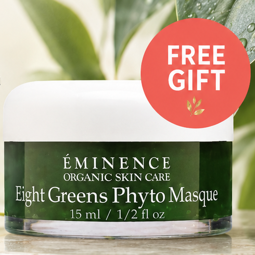 Promotional ad for Eminence Organic Skin Care Eight Greens Phyto Masque, showing a small white jar with a dark green label on a stone surface with green leaves around it. Large text reads 'Replenish Your Home Care' and includes a red 'FREE GIFT' badge and store branding at the bottom.
