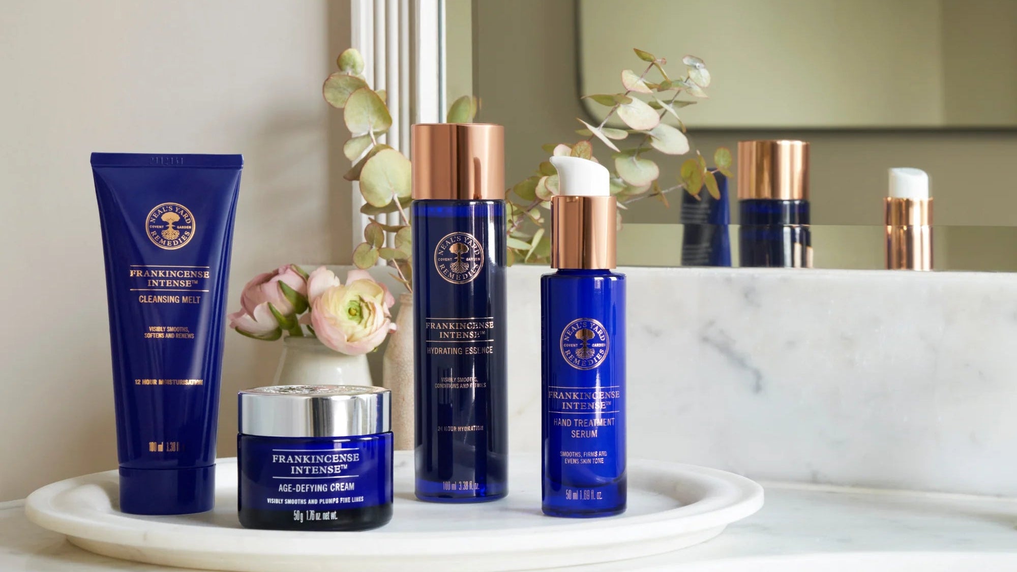 Collection of skincare products on a marble surface with a mirror in the background